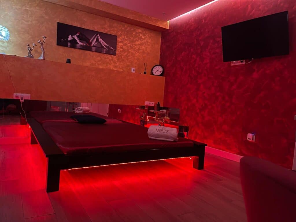 Habitación con cama baja y luces rojas ambiente